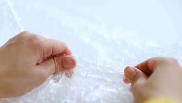 ASMR, woman presses plastic bubble wrap as a stress relief. Popping bubble wrap