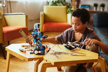 An African-American boy making a robot at home. Education in robotic at home.
