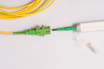 Single mode patch cord with SC-APS connector and adapter, fiber optic cleaner next to the patch cord