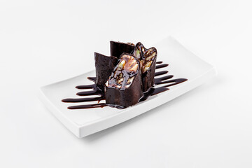 Sweet chocolate dessert in the form of Sushi rolls from traditional Japanese cuisine. White plate on a white background.