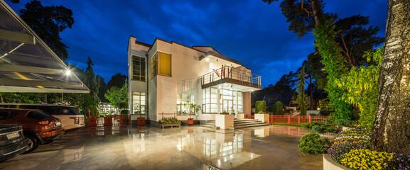 Modern exterior of luxury private house at twilight. Beautiful garden.