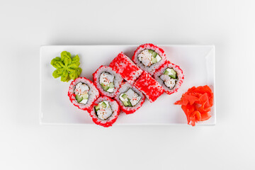 Sushi roll "California" on a white plate with wasabi and ginger. Rice with cucumber, crab sticks and red caviar. White background.