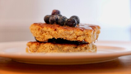 Side view of oatmeal pancake with blueberries and drizzled with honey
