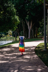 A little girl in a rainbow dress fun running on the concrete path in the park.