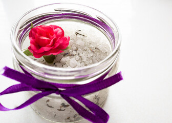 Sea salt bath in a glass jar with a flower. Spa natural cosmetics for the body on a white background