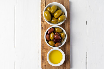 Small bowl with olive oil and olives on white background, top view