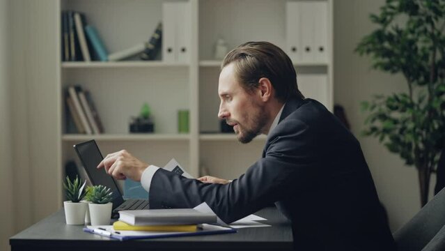 Upset businessman comparing company financial statistics, looking at documents