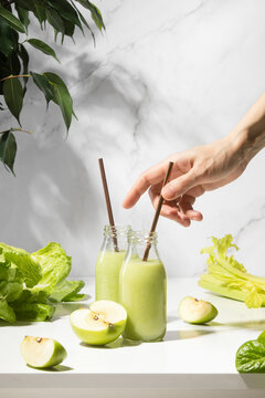 Green detox smoothies in a bottle standing on white table, front view