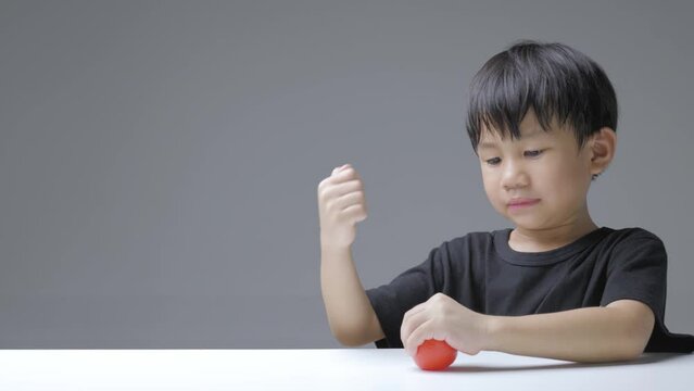 Asian boy squeezes hand therapy ball. A 5 years old doing exercise with a rubber palm stretcher.