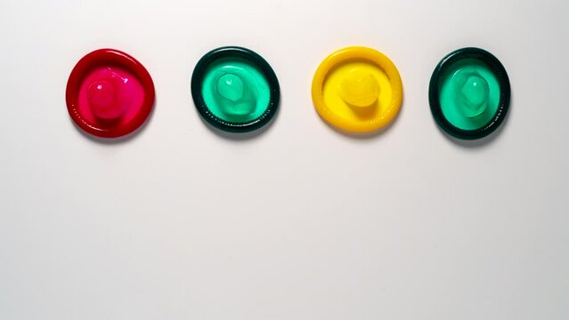 Colour condoms show up on a white table, Stop motion