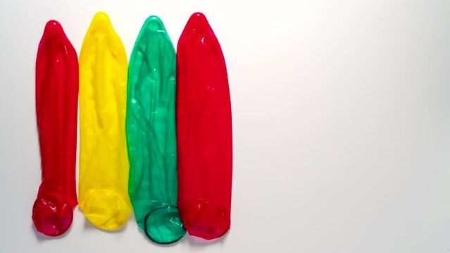 Colour condoms disappear from a white table, Stop motion