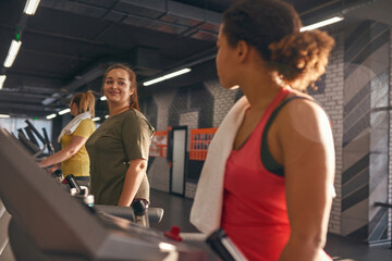 Fototapeta na wymiar Group of girls running on treadmill in sunny gym