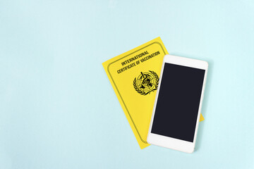 International vaccination record book. Yellow international certificate of vaccination with empty mobile phone.