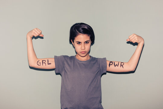 teenager with arms written girl power and symbol of strength