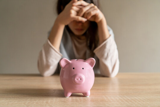 Sad girl with a piggy bank at home.