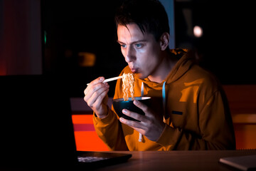 Man is eating noodles and watching movies.