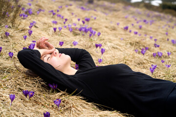 Beautiful girl rests in a meadow full of wild crocuses.
