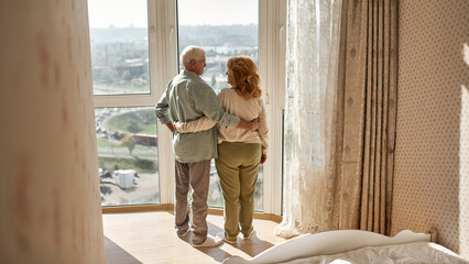 Senior couple looking at each other near window