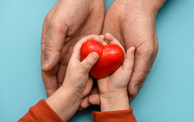 A red heart in the hands of a father and a child. valentine's day. Mother's Day. Love and care .