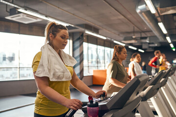 Fototapeta na wymiar Focus on girl run on treadmill with blurred people