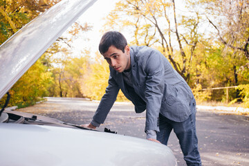 A man looks under the quota of a broken car.