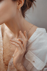 Graceful arms, neck and cheekbones against the background of a white wall with dried flowers.