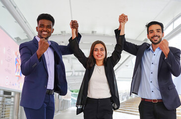 group of young business people clasping hands and raising, the signal of teamwork with happily
