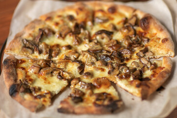 Mushroom pizza with addition mozzarella cheese and herbs on a wooden table,