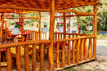 Fototapeta na wymiar outdoor area of a summer cafe made of logs with hanging flowers