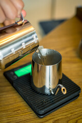 Fototapeta na wymiar Photo of Hand barista poured hot water to kettel and weighing preparing filter coffee.