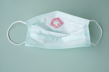 Protective medical face mask with red lipstick kiss print on a green background	