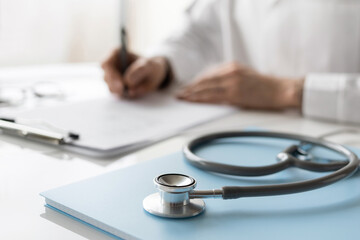 Close-up of doctor medical professional wearing uniform taking notes, physician, therapist or practitioner filling medical documents, writing prescription for patient. Health care, medicine concept