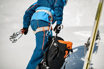 Close-up of the body part of a male tourist in ski suit with climbing harness wearing on.