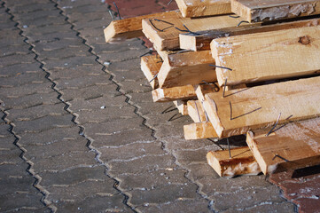 A pile of boards with protruding nails. Winter outdoors. Dismantling of temporary New Year's ice slides after the holiday. Selective focus.