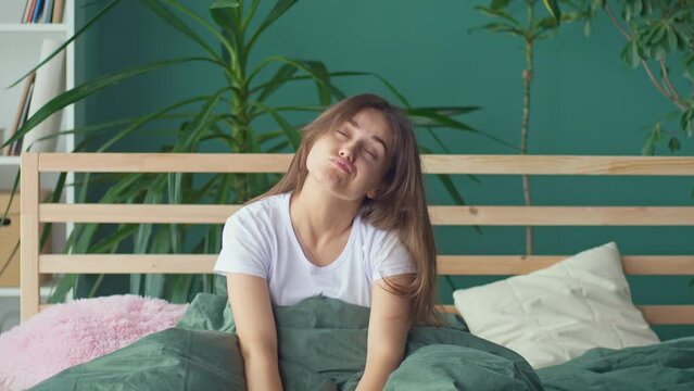 A Young Woman Wakes Up in a Bad Mood in an Uncomfortable Bed At Home, Suffers from Headaches, Insomnia. Uncomfortable Bed or Mattress, Poor Sleep, Stiffness, Pinching in the Neck. Lack of Sleep.