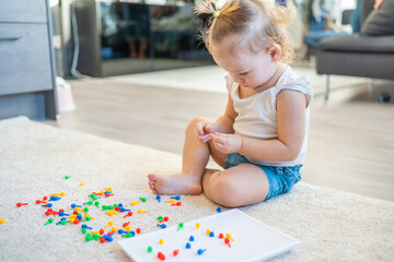 Pretty little girl playing with mushroom nail mosaic at home. Hobby and leisure time