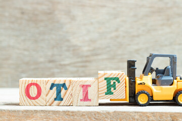 Toy forklift hold letter block f to complete word OTIF (abbreviation of On Time In Full) on wood...