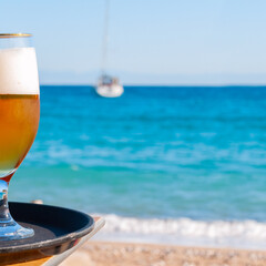 Photo of cold beer glass on the bar table in summer day