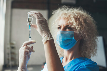 Portrait of a curly nurse extracting the dose needed to vaccinate his patient against covid-19....