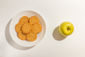 Cookies,Biscuits and green apple on white plate top view on white background.
