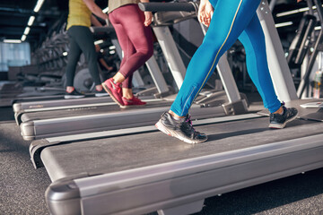 Cropped image of girls running on treadmill in gym