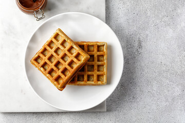 Waffle empty on white plate and marble board with chocolate paste. Top view