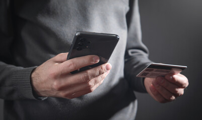 Man using smartphone and holding credit card.
