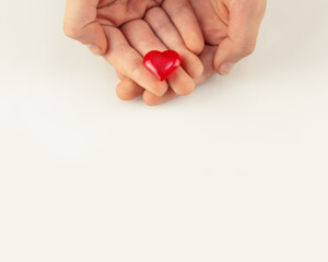 Hands holding a red heart on a white background with a copy space. The concept of healthcare, love, organ donation, mindfulness, insurance. World Heart Day, World Health Day. National Organ Donor Day