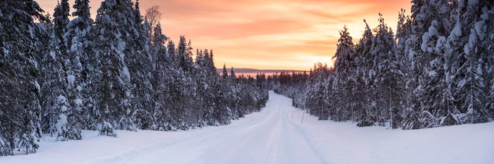 Schilderijen op glas Icy snow covered winter road in the Arctic Circle at sunset in Lapland, Finland © Matthew