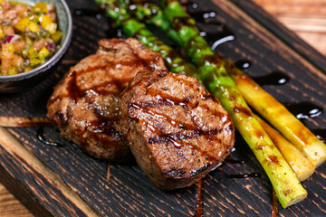 Veal medallions with green beans and chilli pepper on a plate on a wooden background