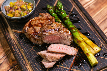 Veal medallions with green beans and chilli pepper on a plate on a wooden background