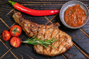 Juicy delicious ribeye or tomahawk steak on the bone with baked potatoes, spices and herbs. Hearty meat dish