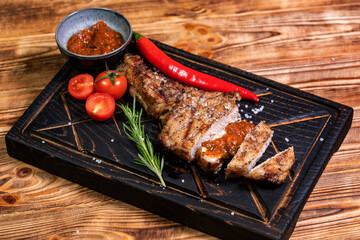 Juicy delicious ribeye or tomahawk steak on the bone with baked potatoes, spices and herbs. Hearty meat dish