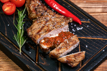 Juicy delicious ribeye or tomahawk steak on the bone with baked potatoes, spices and herbs. Hearty meat dish